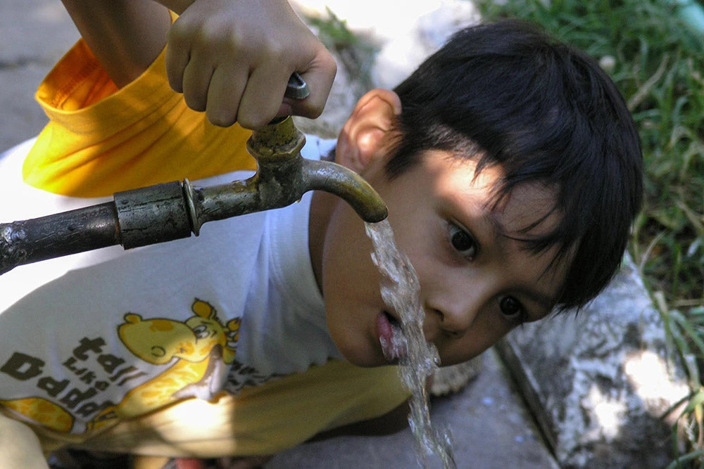 A child drinks water from an outdoor tap in Uzbekistan. Photo credit: World Bank.